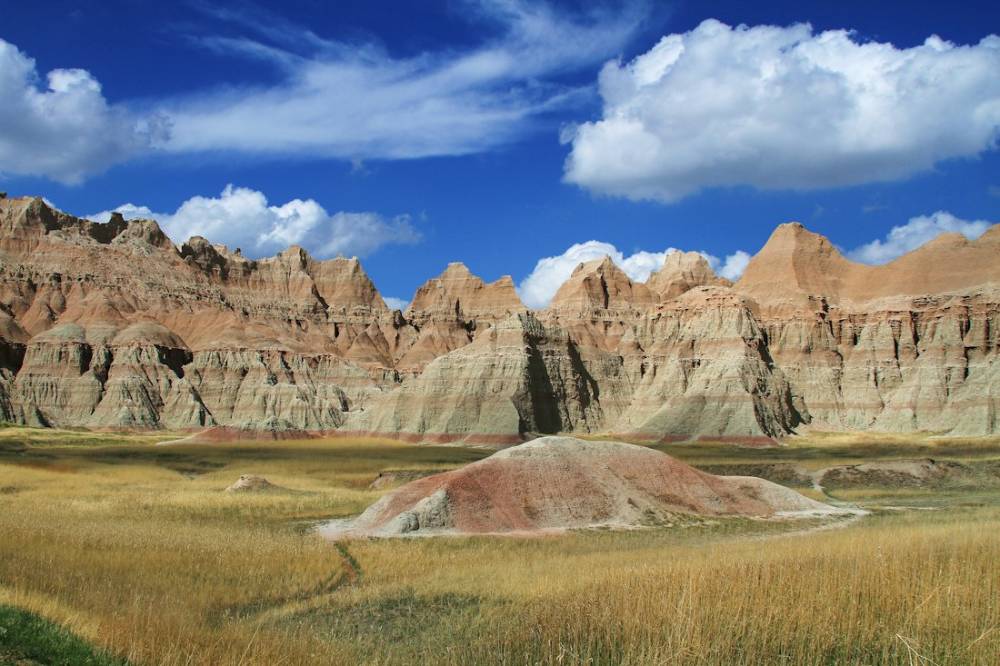 Layered badlands formations rising above prairie grass