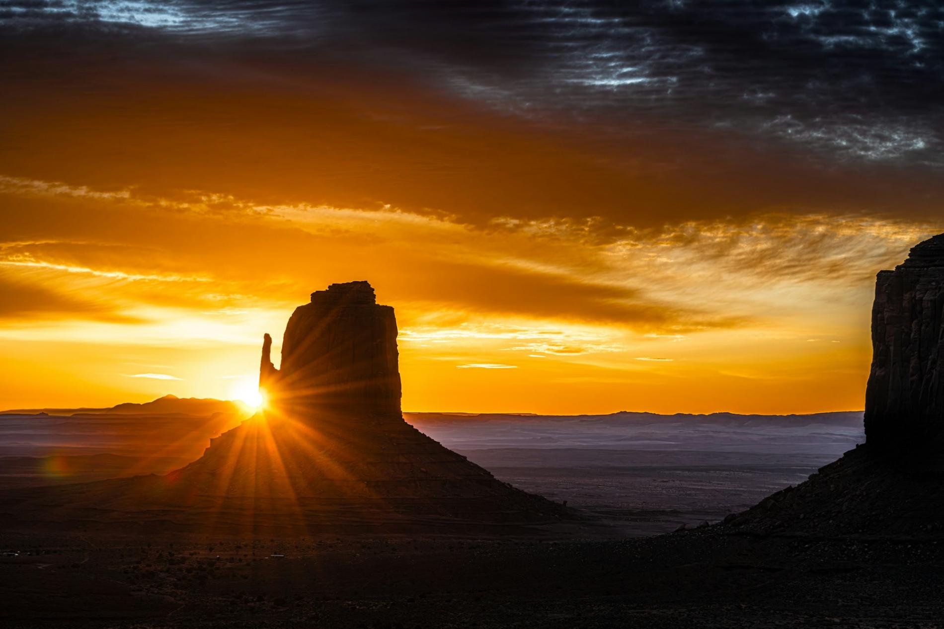 Sunrise breaking beside a sandstone butte in the desert Southwest